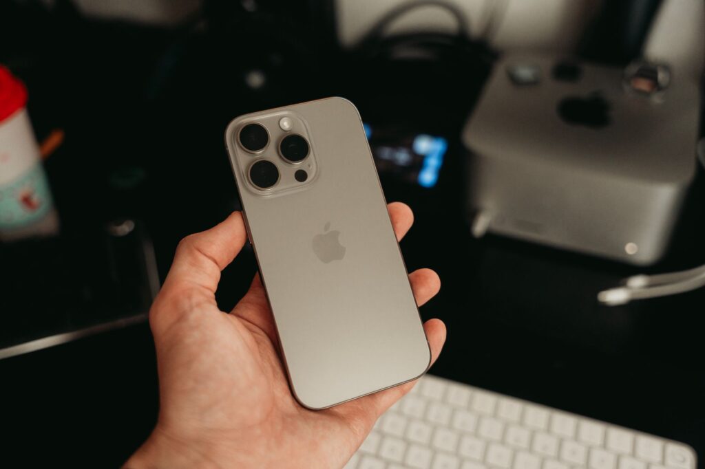 Mano sosteniendo un iPhone Pro en entorno de oficina tecnológica