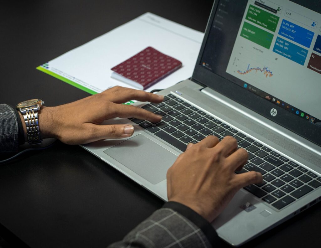 Manos trabajando en laptop con dashboard de métricas digitales — gestión profesional de redes sociales