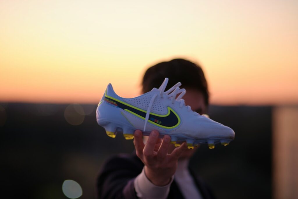 Persona sosteniendo un botín de fútbol Nike al atardecer, simbolizando la campaña de marketing de Nike Football